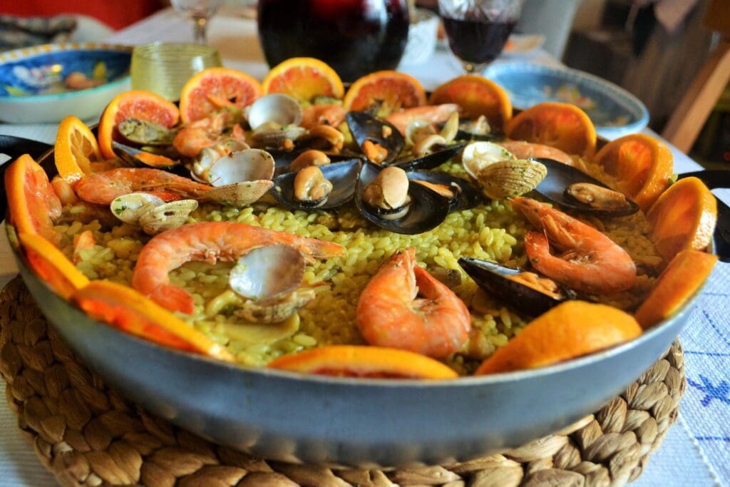 A paella with seafood and orange slices.