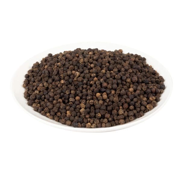 Black peppercorns on a white plate in color.