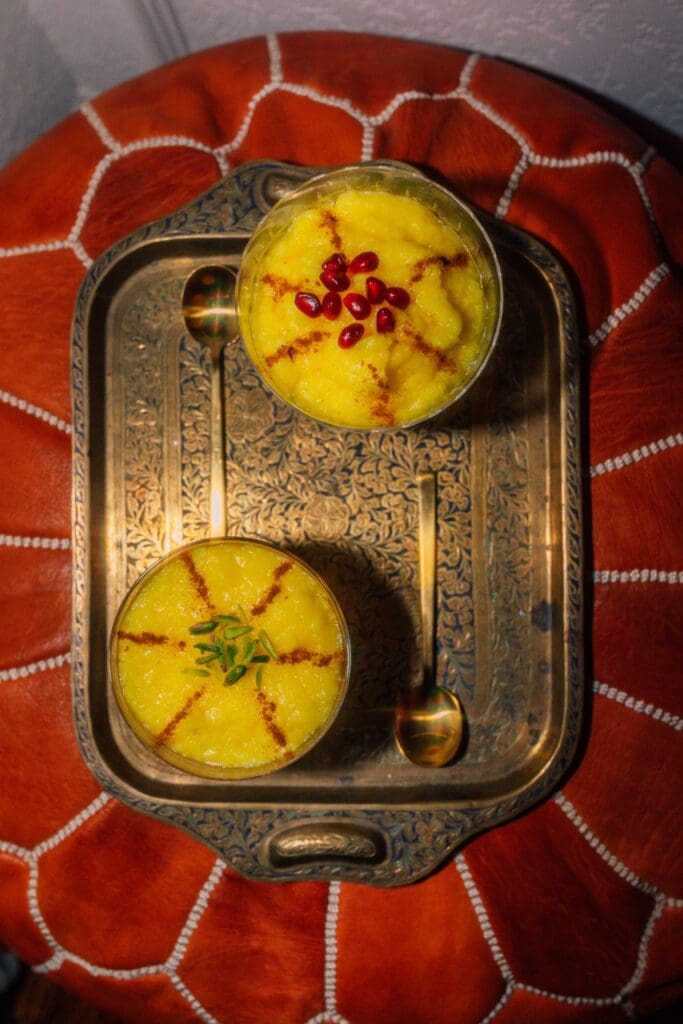 Two bowls of rice pudding on a golden tray.