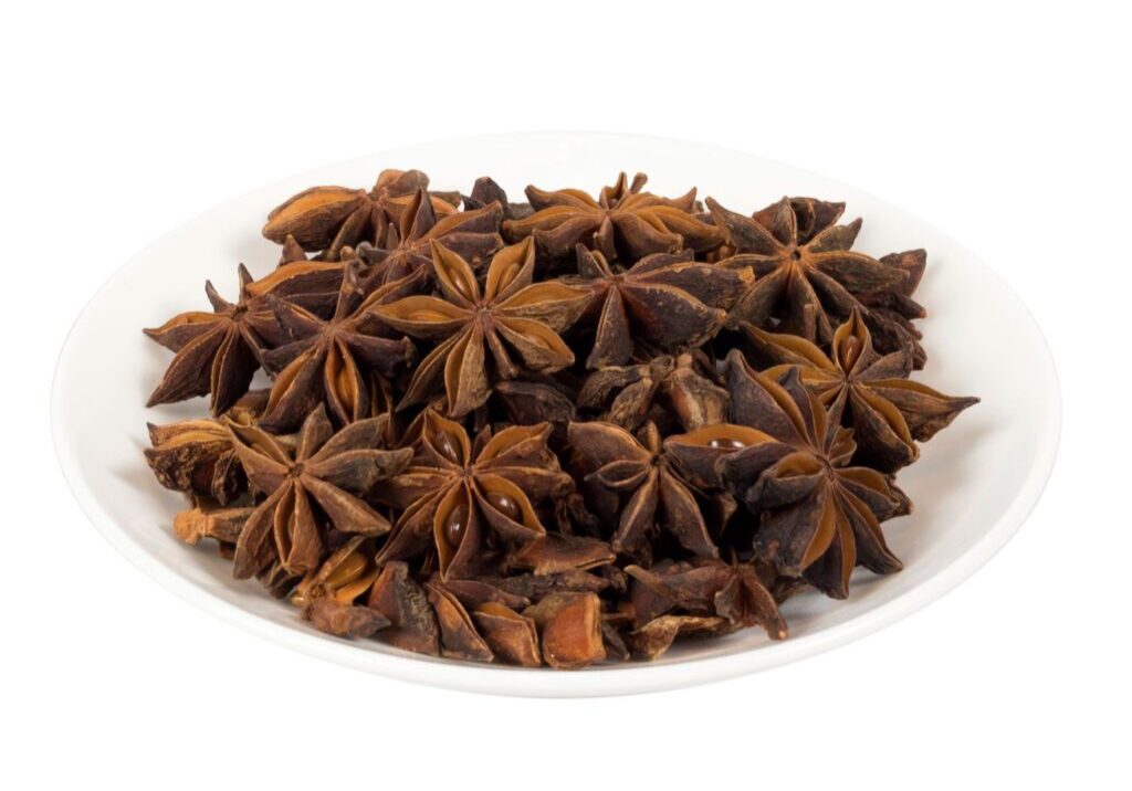 Star anise spice on a white plate in color.