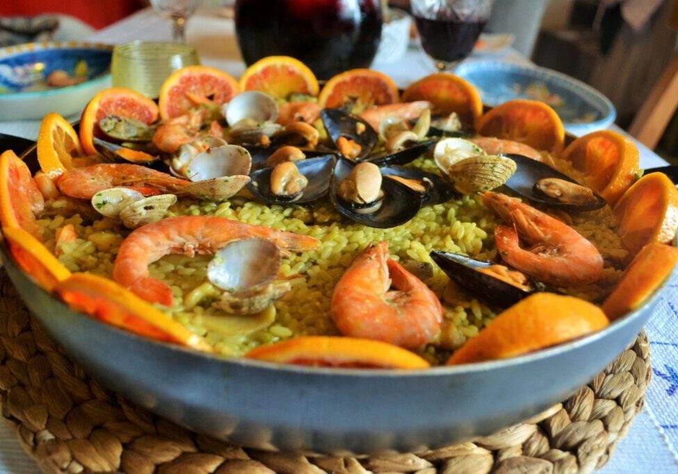 A paella with seafood and orange slices.