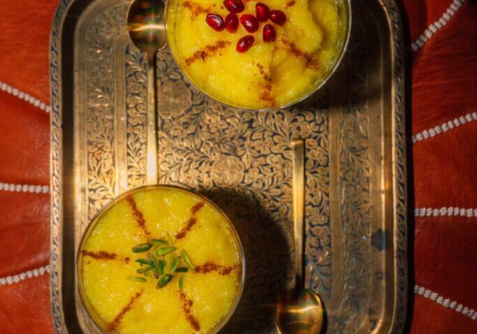 Two bowls of rice pudding on a golden tray.